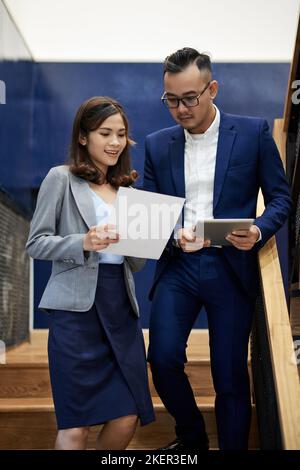 Young business woman showing her ideas to coworker when they are standing on steps Stock Photo