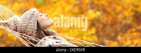 Side view banner of a woman resting in hammock in autumn holiday in a forest with orange background Stock Photo