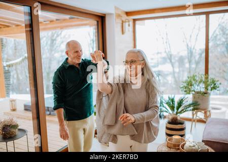 Senior couple in love dancing together in their modern living room. Stock Photo