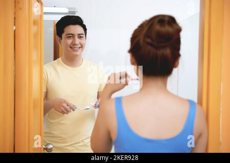 Cheerful young Asian couple brushing teeth together Stock Photo