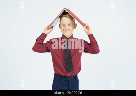 Pupil put an open book on his head and smiles, isolated background. Education concept Stock Photo