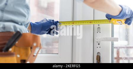 Young worker repairing window in flat. Stock Photo