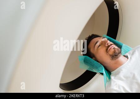 high angle view of brunette man lying during scanning on computed tomography machine,stock image Stock Photo