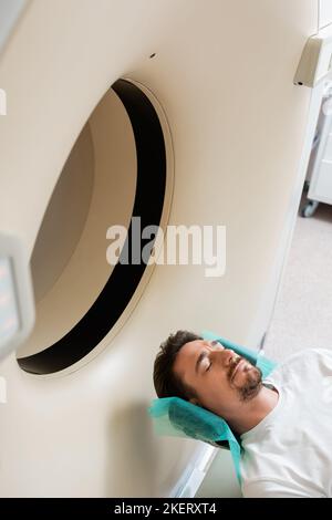 high angle view of brunette man lying during scanning procedure on computed tomography machine,stock image Stock Photo