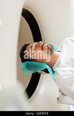 bearded man with closed eyes lying during diagnostics on computed tomography machine,stock image Stock Photo