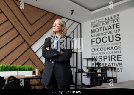 woman company owner businesswoman stands in the middle of the office and looks thoughtfully out the window Stock Photo
