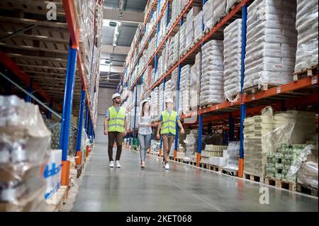 Serious female supervisor and warehouse employees inspecting a racking system Stock Photo