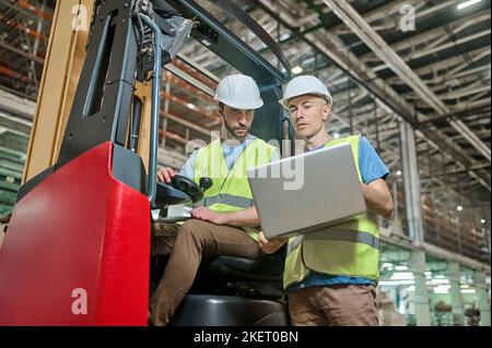 Men in protective helmets working in a storage area Stock Photo