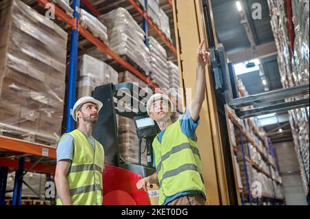 Warehouse personnel in protective helmets inspecting a racking system Stock Photo