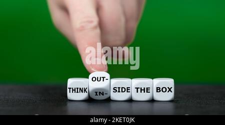 Hand turns dice and changes the expression 'think inside the box' to 'think outside the box'. Stock Photo