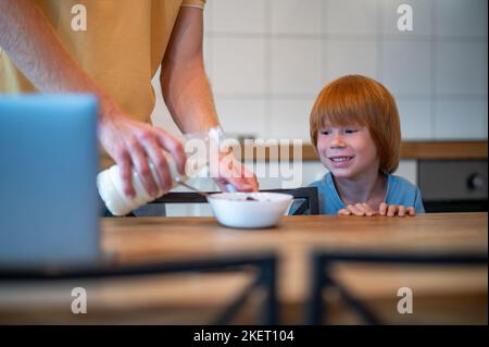 Man pouring milk into the plate of his son Stock Photo