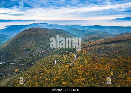 Panoramic view of the mountains covered with forests in the autumn aura. Autumn over the mountains with a thick morning fog in the background. A windi Stock Photo