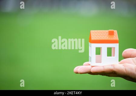 Real estate idea concept, woman holding white house figure in her palm. Horizontal photo with text area on the left. Copy space, space for text. Stock Photo