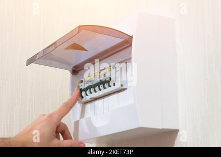 Circuit breaker board displays many switches. A finger is about to turn it back on. Stock Photo