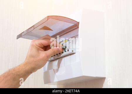 Circuit breaker board displays many switches. A finger is about to turn it back on. Stock Photo