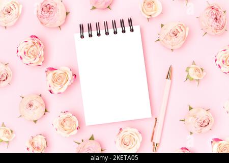 Empty notepad mockup. Stationery and rose flowers on a pink pastel background. Stock Photo