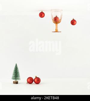 Upside down perspective with Christmas baubles, vintage drinking glass and tree on white background. Minimal New Year concept. Stock Photo