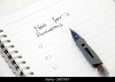 Writing new year’s resolutions, list on white notepad with ballpoint pen. Setting goals for the new year. Stock Photo