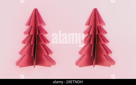 Two pink paper origami christmas trees on pink background isolated. Stock Photo