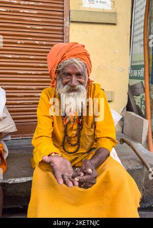 Pushkar, Rajasthan, India - November 2022: Portrait of an old  sadhu baba on the street of Pushkar in traditional saffron dress with white beard. Stock Photo