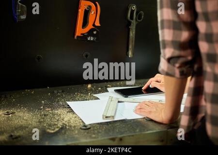 Female business owner using digital tablet in workshop, industrial woman engineer working with blueprints and tablet in the workshop. Stock Photo