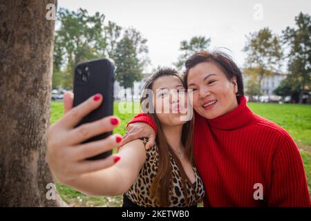Two Asian friends take a selfie in an open-air park, happy mature chinese females Stock Photo