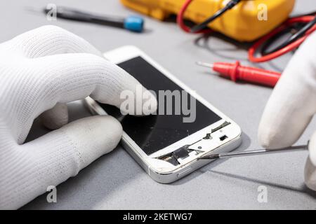 Technician hands working on broken smartphone for repair or replace new part on desk. Close up Stock Photo