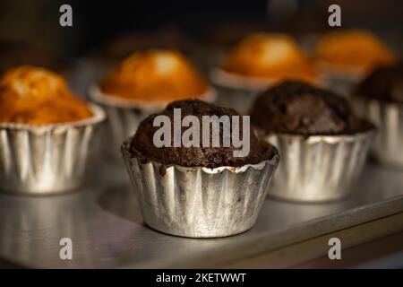 Freshly baked muffins in metal molds close-ups in a bakery. Stock Photo
