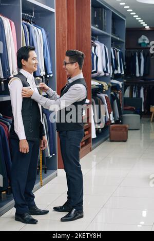 Happy tailor measuring jacket on male client Stock Photo