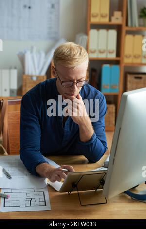 Pensive investor reading business offer on tablet computer Stock Photo