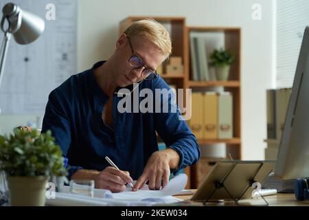 Engineer taking notes when talking to client on the phone Stock Photo