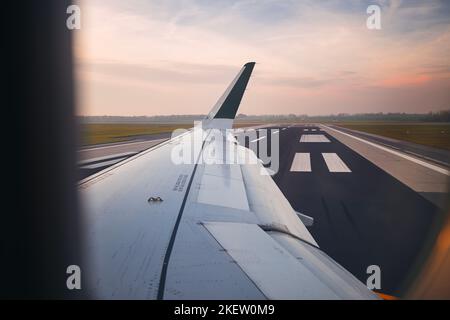 View from airplane window at airport at sunset. Plane during taxiing to runway before take off. Stock Photo
