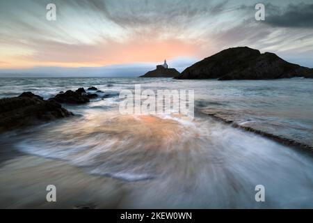 Sunrise over Mumbles lighthouse in Swansea Bay, South Wales UK Stock Photo