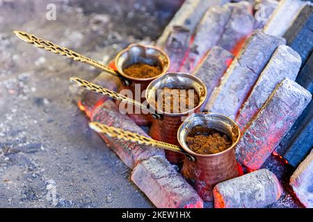 Turkish coffee cooked on embers. Street vendor cooks Turkish coffee on embers. Traditional pottery and Turkish coffee cups are used. Shot in a cafe in Stock Photo