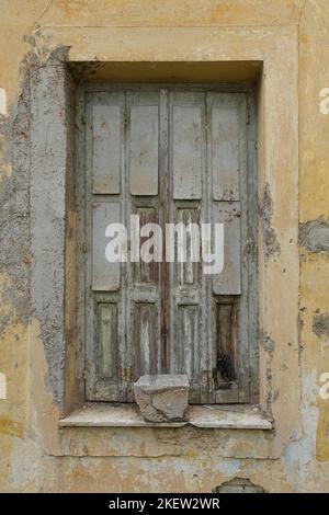 Old window with wooden shutter and weathered wall of an abandoned house. Stock Photo