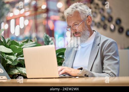 Busy older senior business man using laptop working late on computer. Stock Photo