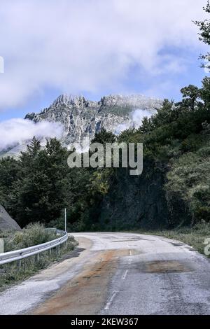narrow bad road through the forest next to the trees in the direction of the impressive rocky mountains, ruta del cares asturias, spain Stock Photo