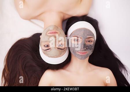 Two girls are relaxing during facial mask application in spa Stock Photo