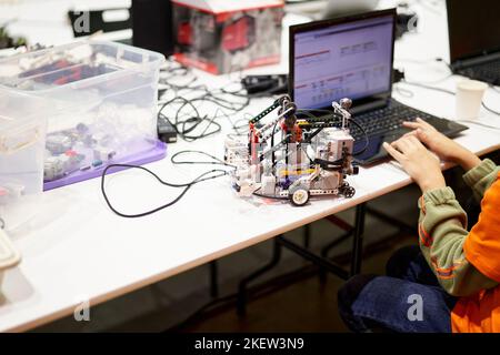 The hands of a student, a schoolboy, building robotic vehicles, robotic cars, used educational software applications for computers. A child studying programming is sitting at a table in a STEAM engineering programming lesson. Stock Photo