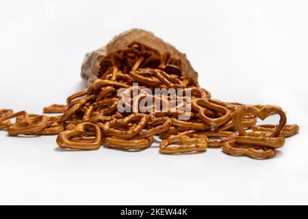 Heart-shaped salty pretzel snacks spilled from the paper bag on white Stock Photo
