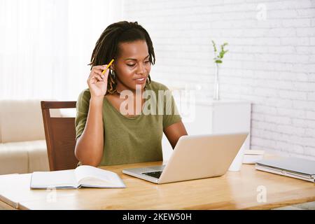 Pensive female outsourse programmer working on laptop Stock Photo