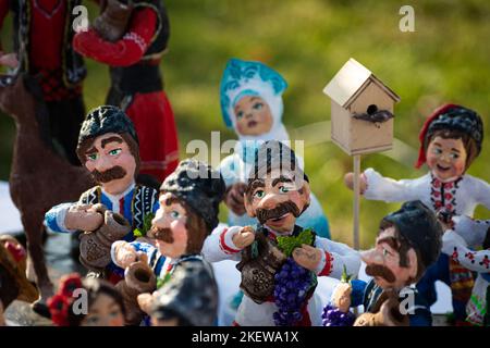 Assortment of clay souvenirs. Souvenir clay figurines of men in national Moldovan costumes with jugs and grapes in their hands. Moldavian folk art on Stock Photo
