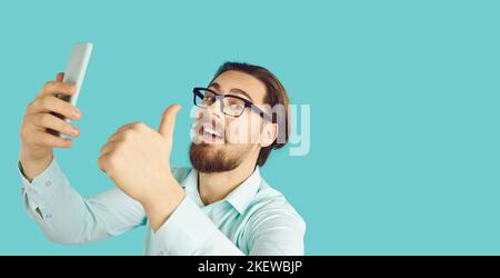 Happy man isolated on copy space banner background using cellphone and showing thumbs up Stock Photo