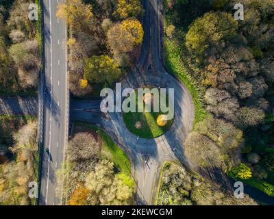 Aerial view of a highway junction surrounded by lush green hills ...