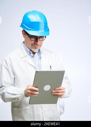 Middle age engineer in lab coat and hard hat. Scientist, architect with tablet. Mid adult, mature age man, happy smiling. Portrait isolated on white. Stock Photo