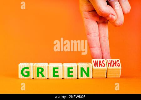 Green or greenwashing symbol. Concept words Green and Greenwashing on wooden cubes. Businessman hand. Beautiful orange table orange background. Busine Stock Photo