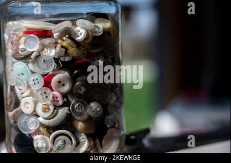 assortment random colored loose buttons in a glass jar Stock Photo