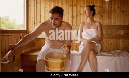 Couple relaxing in hot sauna. Authentic, real sauna moment. Stock Photo