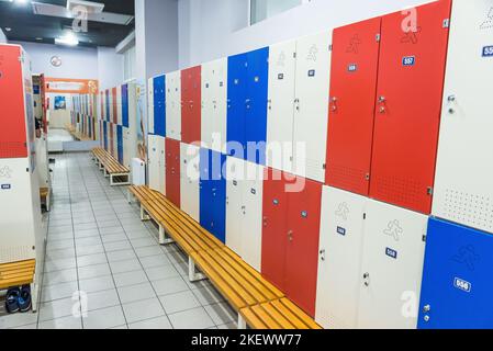 Red lockers in generic locker room with wooden bench red blue white style Stock Photo