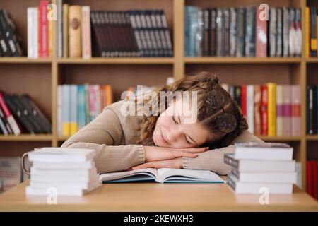 Young women got asleep on the books while studying, reading glasses on head Stock Photo